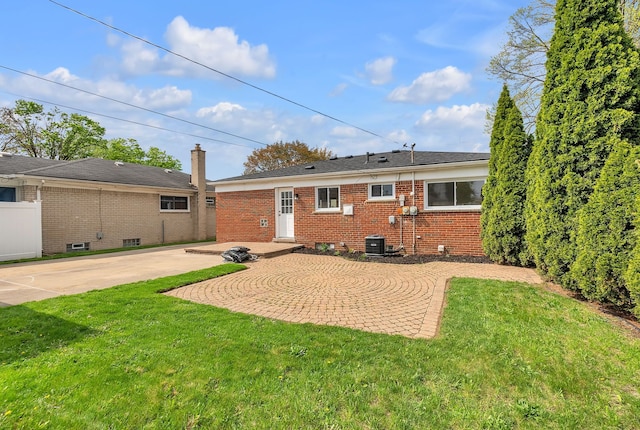 rear view of property with a yard, central air condition unit, a patio, and brick siding