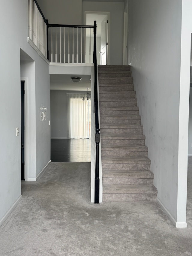 stairs with baseboards, a high ceiling, and carpet floors