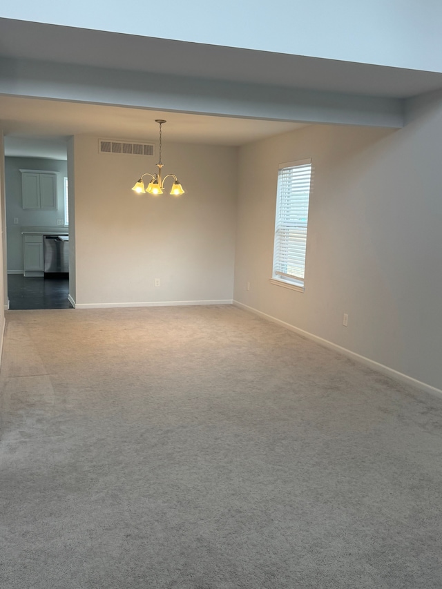 empty room with a chandelier, carpet floors, baseboards, and visible vents