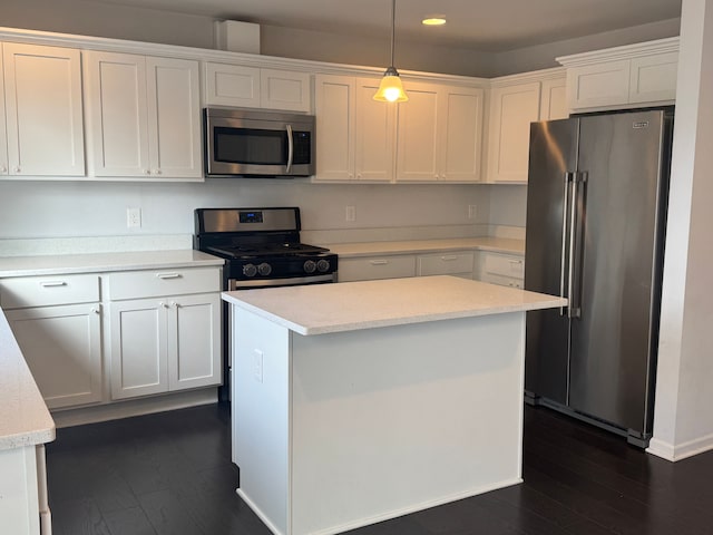 kitchen featuring stainless steel appliances, decorative light fixtures, dark wood-type flooring, white cabinetry, and a kitchen island