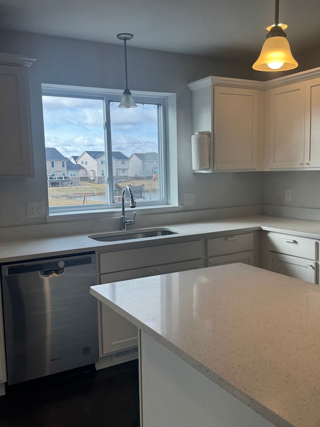 kitchen featuring a sink, white cabinets, dark wood finished floors, stainless steel dishwasher, and decorative light fixtures