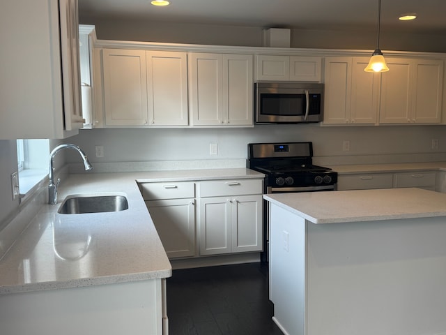 kitchen with hanging light fixtures, a sink, white cabinets, appliances with stainless steel finishes, and recessed lighting