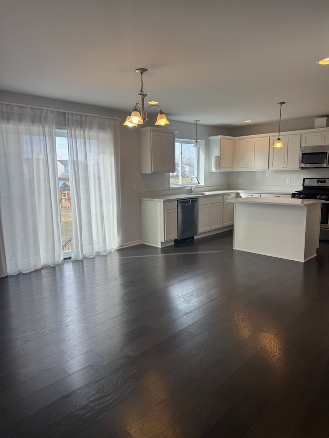 kitchen with light countertops, appliances with stainless steel finishes, dark wood-style floors, and a notable chandelier