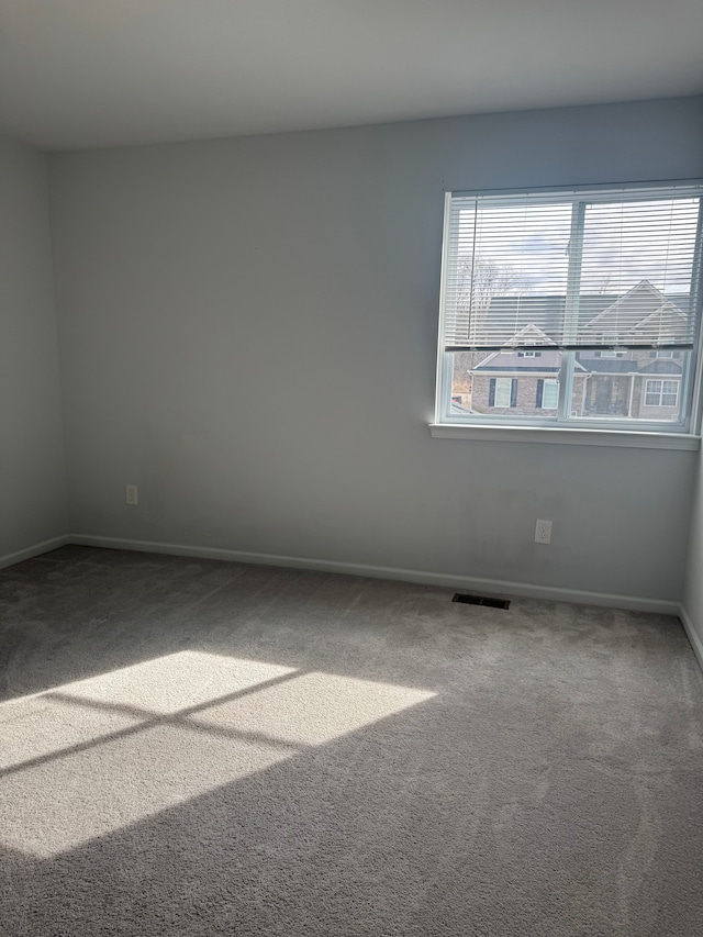 unfurnished room with baseboards, carpet flooring, and visible vents