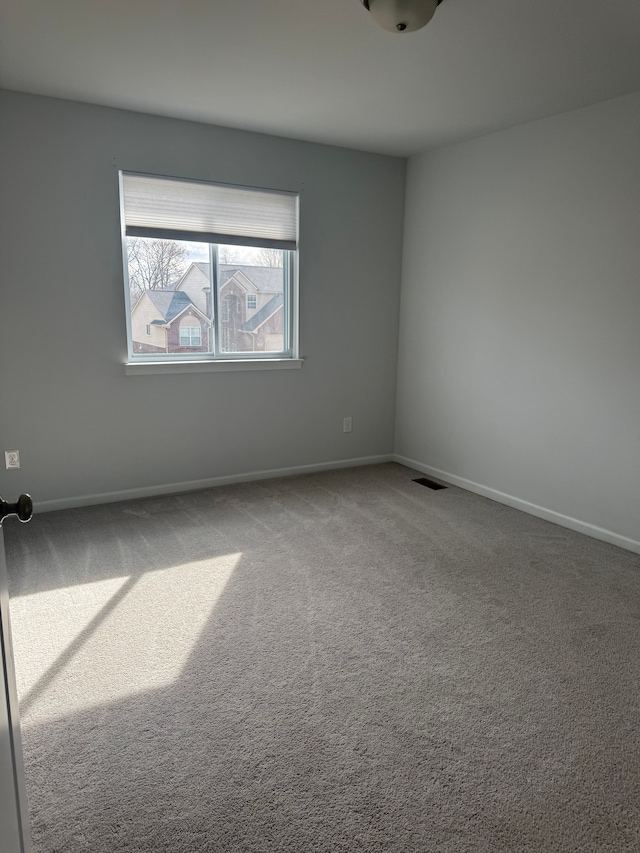 empty room with baseboards, visible vents, and carpet floors