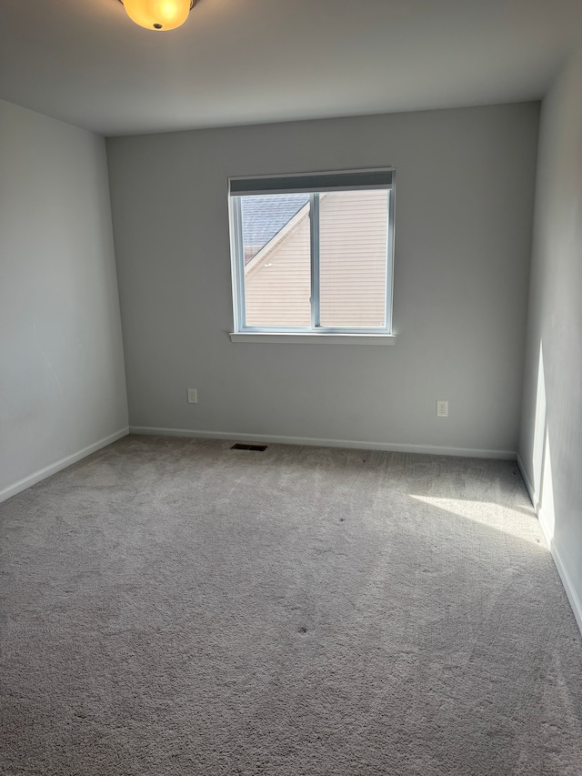 spare room featuring carpet flooring, baseboards, and visible vents