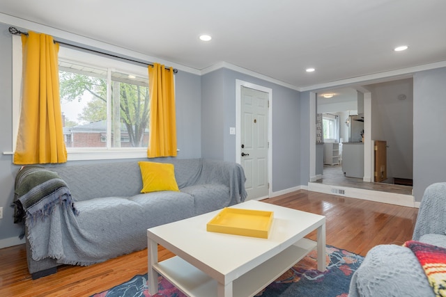 living area with wood finished floors, ornamental molding, recessed lighting, plenty of natural light, and baseboards