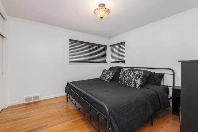 bedroom with light wood-type flooring, crown molding, and baseboards