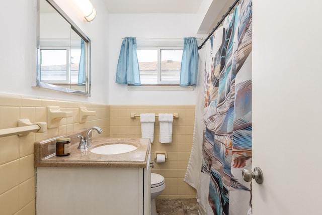 full bathroom with tile walls, toilet, vanity, a wainscoted wall, and a shower with shower curtain