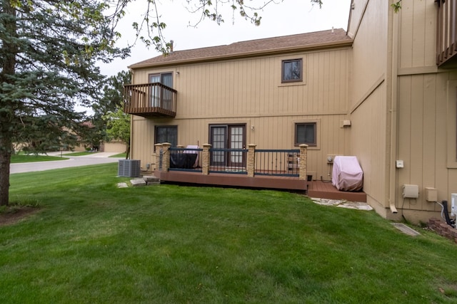 back of house with a balcony, a lawn, central AC unit, a deck, and roof with shingles