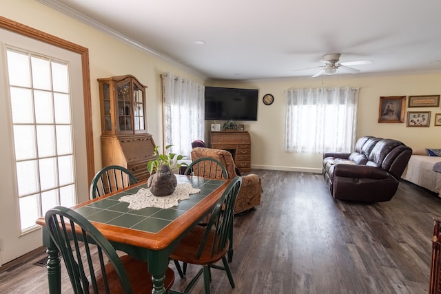 dining space featuring a ceiling fan, ornamental molding, baseboards, and wood finished floors