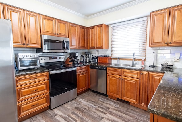 kitchen featuring a sink, a toaster, crown molding, appliances with stainless steel finishes, and tasteful backsplash