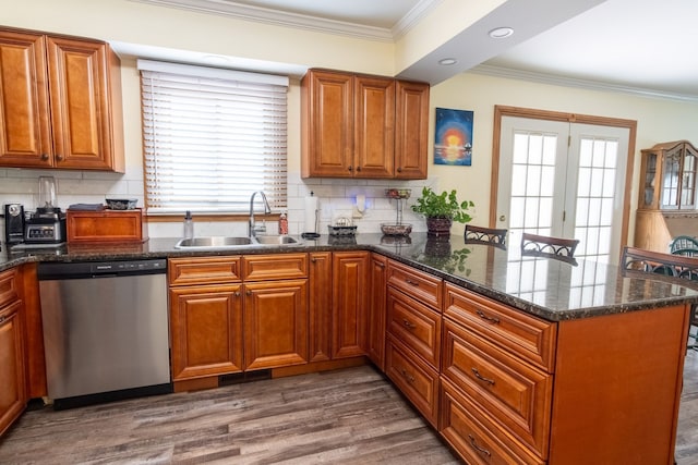 kitchen featuring a peninsula, wood finished floors, a sink, stainless steel dishwasher, and ornamental molding