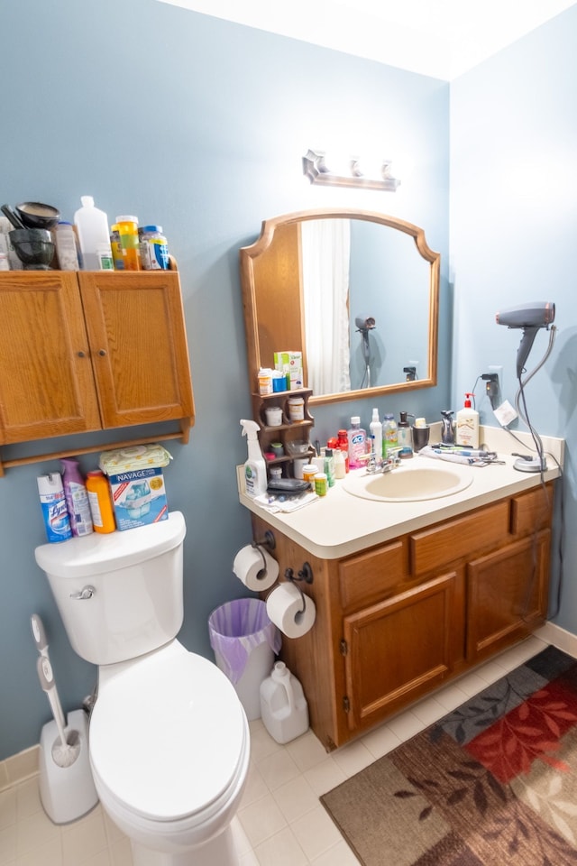 half bath with vanity, toilet, and tile patterned flooring