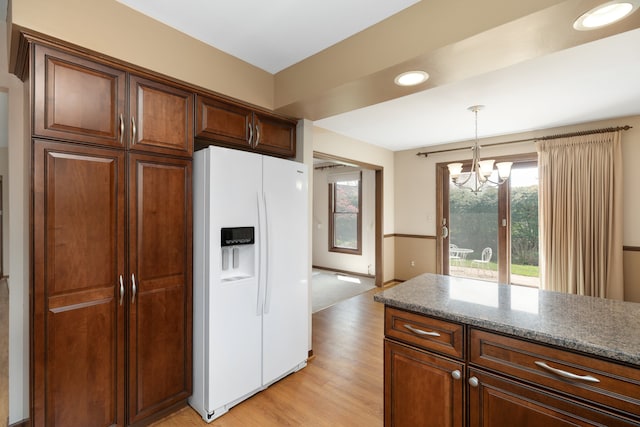 kitchen featuring stone counters, pendant lighting, a notable chandelier, white refrigerator with ice dispenser, and light wood-style floors