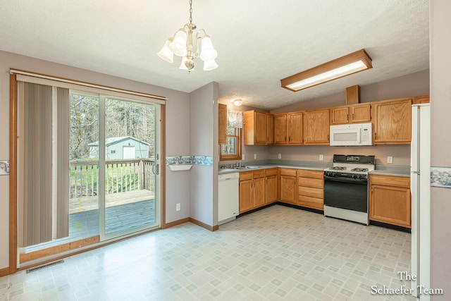 kitchen featuring visible vents, white appliances, light countertops, a chandelier, and lofted ceiling