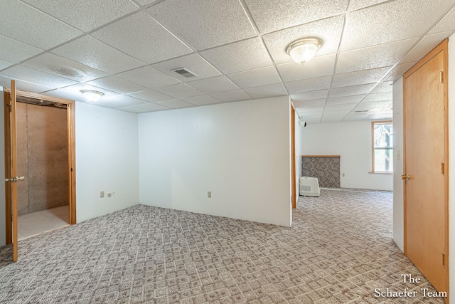below grade area with carpet, visible vents, and a drop ceiling