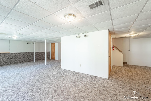 finished below grade area with a drop ceiling, carpet flooring, and visible vents