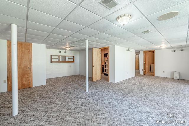 finished below grade area with a drop ceiling, visible vents, and carpet floors