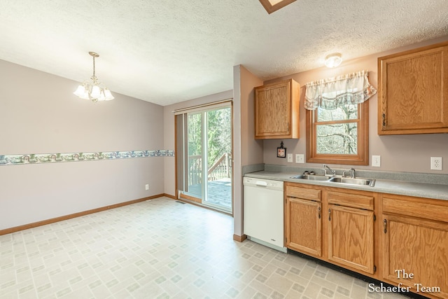 kitchen featuring hanging light fixtures, a sink, baseboards, light countertops, and white dishwasher