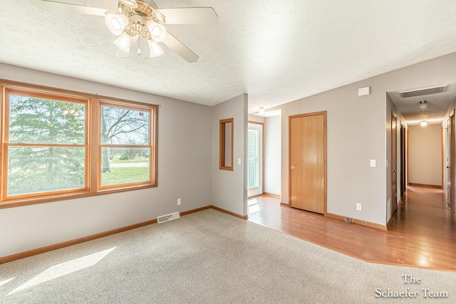 unfurnished room with ceiling fan, carpet flooring, baseboards, and visible vents