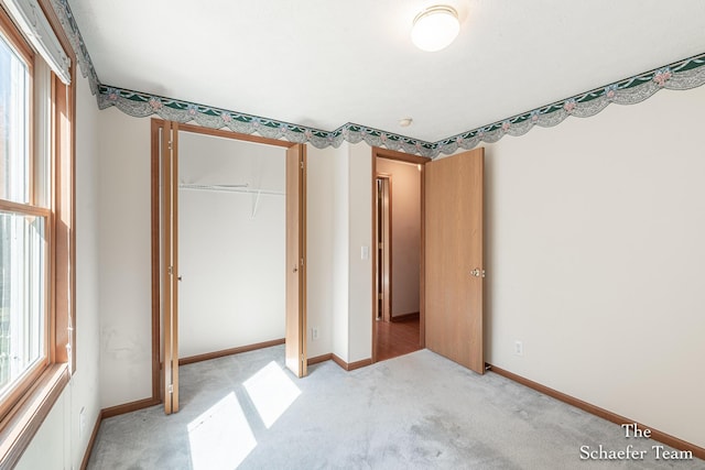 unfurnished bedroom featuring light colored carpet, a closet, baseboards, and multiple windows