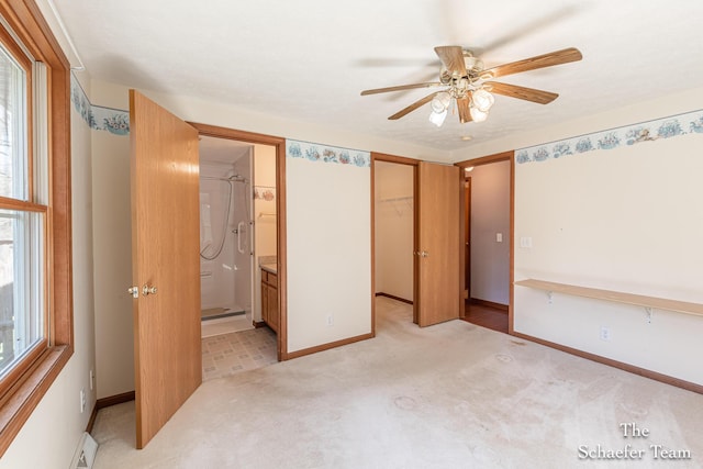 unfurnished bedroom featuring a closet, ensuite bathroom, baseboards, ceiling fan, and light carpet