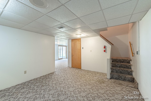 below grade area with a drop ceiling, stairway, visible vents, and carpet
