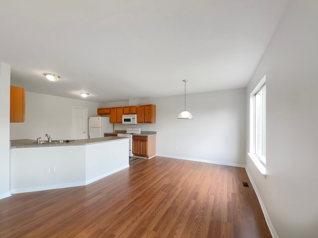 1555 S Harris Rd, Ypsilanti, MI 48198 - kitchen with brown cabinetry, baseboards, white appliances, a peninsula, and wood finished floors