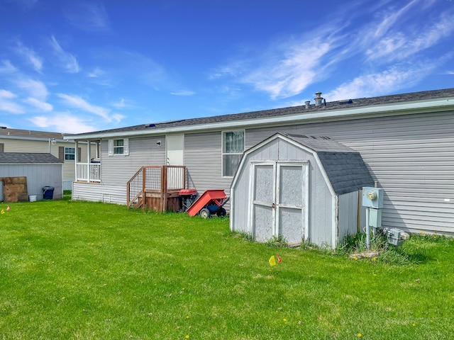 rear view of property featuring a storage unit, a lawn, and an outbuilding