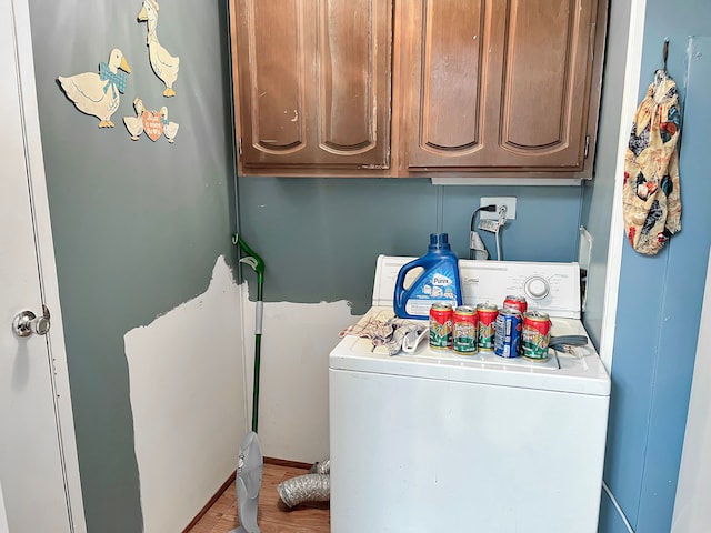 clothes washing area featuring washer / clothes dryer, cabinet space, and wood finished floors