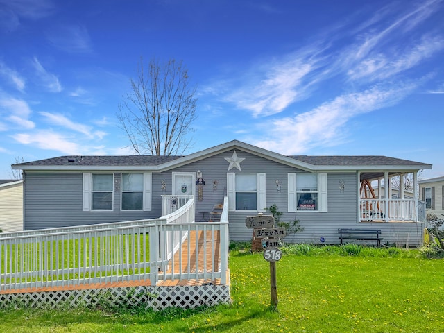 manufactured / mobile home featuring a front yard, a shingled roof, and a wooden deck