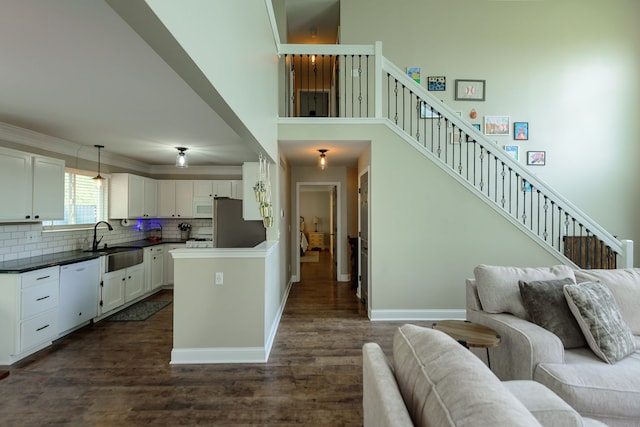 kitchen with a sink, open floor plan, white appliances, backsplash, and dark wood finished floors