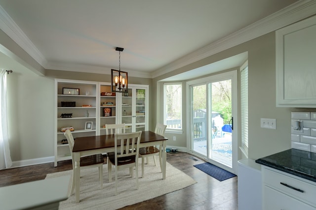 dining room with a chandelier, dark wood-style flooring, ornamental molding, and baseboards
