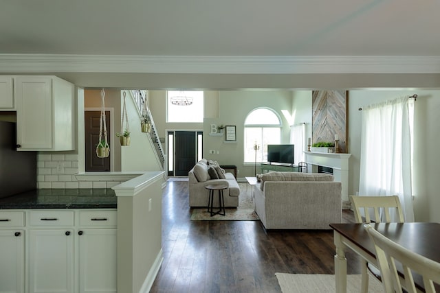 living area featuring dark wood-style flooring, crown molding, a fireplace, and stairs