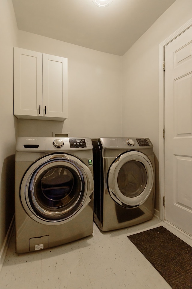 washroom featuring cabinet space and washer and clothes dryer
