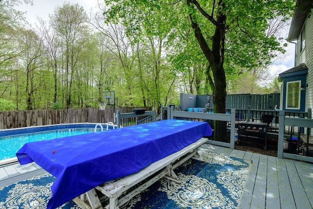 view of swimming pool featuring a wooden deck, a fenced backyard, and outdoor dining space