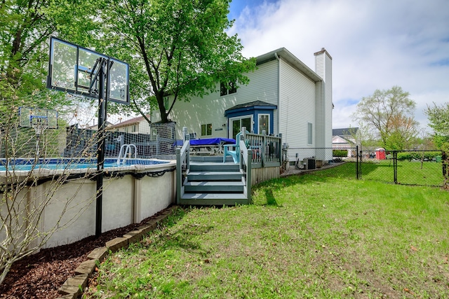 back of property with a chimney, a wooden deck, an outdoor pool, a gate, and central air condition unit