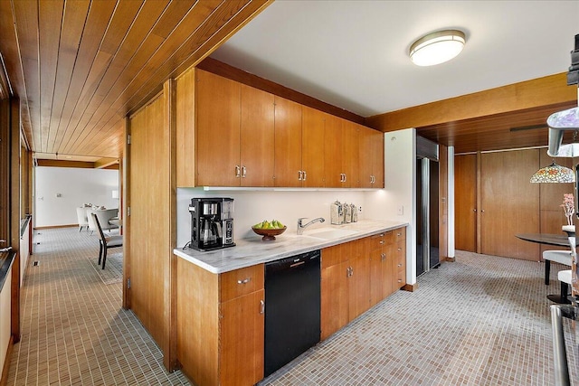 kitchen featuring brown cabinets, a sink, black dishwasher, light countertops, and fridge