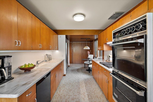 kitchen with visible vents, a sink, dishwashing machine, brown cabinets, and light countertops