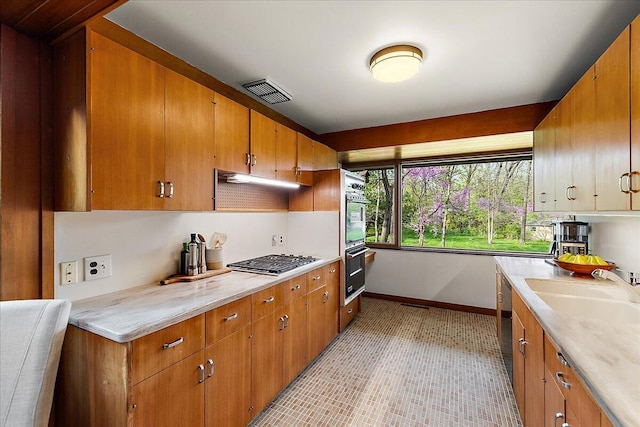 kitchen with baseboards, visible vents, a sink, light countertops, and appliances with stainless steel finishes