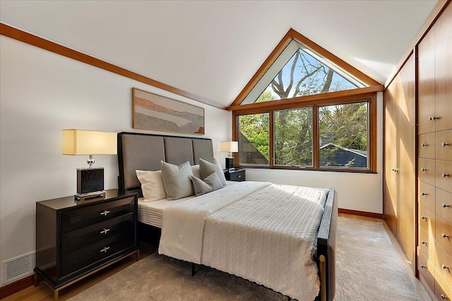 bedroom with baseboards, light carpet, visible vents, and vaulted ceiling
