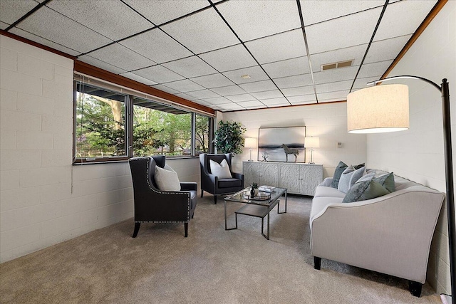 living room with carpet flooring, visible vents, and concrete block wall