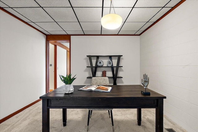 carpeted home office with baseboards and concrete block wall