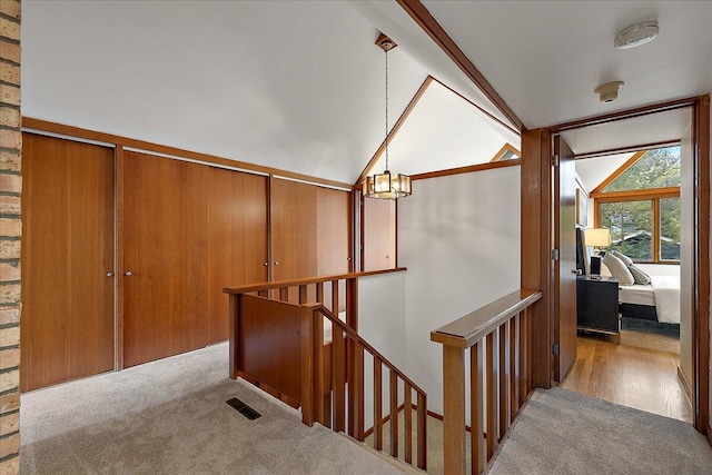 staircase with vaulted ceiling, a chandelier, carpet flooring, and visible vents