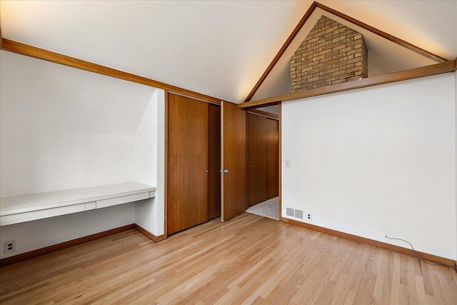 unfurnished bedroom featuring a closet, visible vents, vaulted ceiling, light wood-style flooring, and baseboards