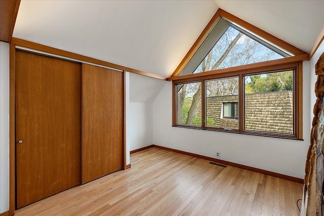 additional living space with lofted ceiling, baseboards, visible vents, and light wood-type flooring