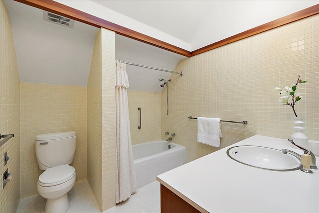 bathroom featuring toilet, tile walls, visible vents, vaulted ceiling, and vanity