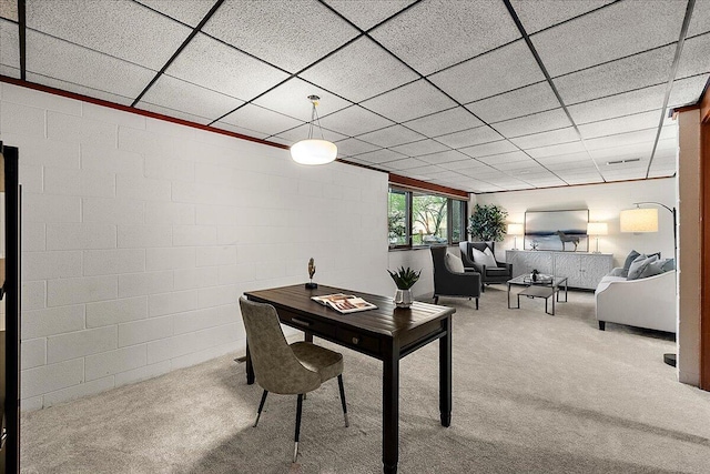 home office with a drop ceiling, carpet, and concrete block wall