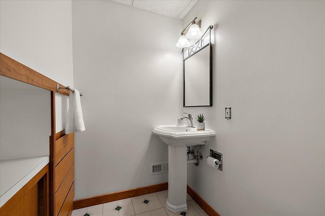 bathroom with a sink, baseboards, visible vents, and tile patterned floors